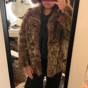 Brun pälsjacka - Säljer en snygg brun pälsjacka med lång ärm och en klassisk look. Jackan har svarta läderremsor under ärmarna, se sista bilden. Obs! Stygnen på insidan är lite slitna
