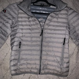 Superdry jacka - Väldigt stilren och värmande jacka funkar perfelt för regn höst eller kyliga dagar, den har en zip längst upp där man kan dra ut en luva för att skydda huvudet skulle verkligen rekommendera jackan, den har stått i garderoben i snart ett år