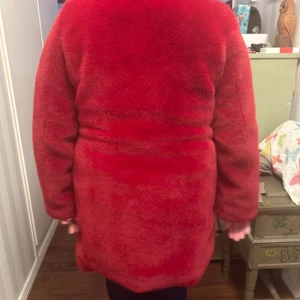 Röd teddyjacka - Säljer en mysig röd teddyjacka med långa ärmar och en fluffig look. Perfekt för att hålla sig varm och stilren under kyliga dagar. Jackan har en enkel design utan synliga detaljer som dragkedjor eller knappar.            Karen Millen är designern.  Storlek 40. Använd 1 gång. 