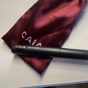 Svart mascara från CAIA - Snygg svart mascara från CAIA med texten 'IRRESISTIBLE' . Kommer i en vinröd påse med CAIA-logga. Perfekt för att ge dina fransar volym och definition.