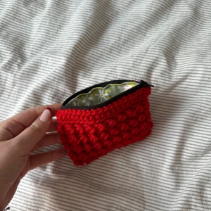 Virkad necessär  - Egentillverkad virkad necessär i ett rött garn med innertyg och dragkedja. Höjd ca 9 cm längd ca 13 cm
