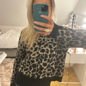 Leopardmönstrad tröja - Säljer en snygg leopardmönstrad tröja med långa ärmar. Tröjan är perfekt för att ge en trendig look. Den är i en neutral färgskala med svart och beige, vilket gör den lätt att matcha med olika outfits.