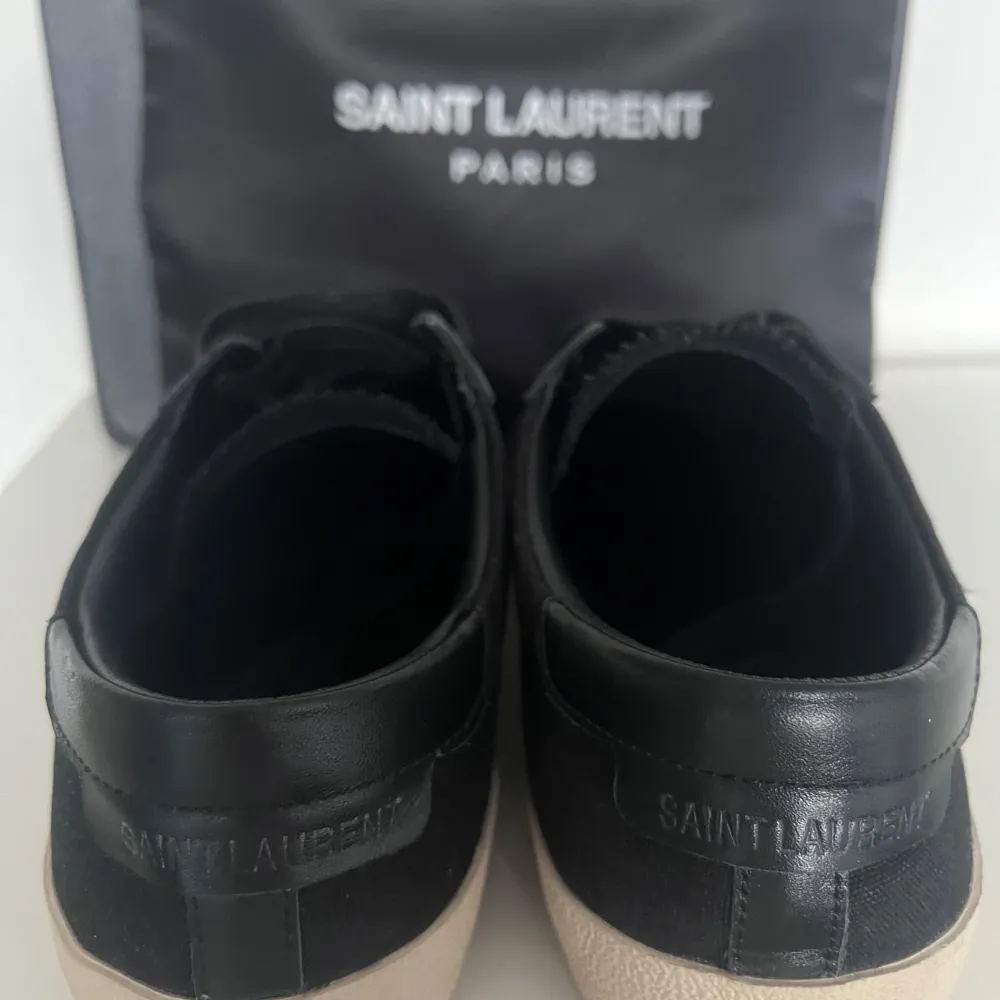 Snygga svarta sneakers från Saint Laurent med vit logga på sidan. Skorna är i ett ny skick, använda få tal gånger. Skorna har en klassisk design med snörning och en beige sula. Perfekta för en stilren look. Box och dustbag ingår! Kontakta mig vid minsta fråga😃. Kengät.