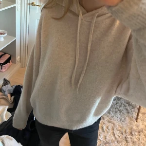 Beige stickad hoodie - Mysig beige hoodie med långa ärmar och dragsko i huvan. Perfekt för en avslappnad stil och passar bra till jeans eller leggings. Helt slutsåld 