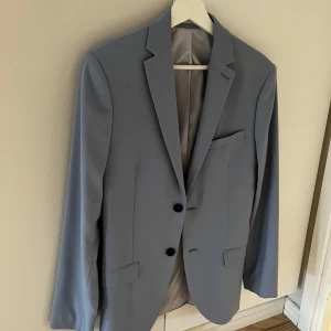 Ljusblå kavaj - Snygg ljusblå kavaj med två knappar framtill och klassiska slag. Perfekt för en stilren look. Passar bra till både formella och semi-formella tillfällen.