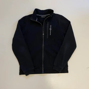 Svart Sail Racing zip - Svart sail racing zip up hoodie, Storlek 170cm motsvarar S, Mycket bra skick, Pris kan diskuteras, Skriv vid minsta fråga eller fundering💯👍
