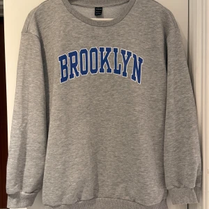 Grå sweatshirt med Brooklyn-tryck - SHEIN - Använd ett fåtal ggr, bra skick. Storlek S. Normal i storleken.