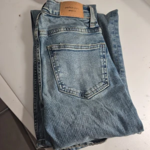 Blå jeans från Gina Tricot - Säljer ett par klassiska blå jeans från Gina Tricot. De har en bootcut-stil och är perfekta för en avslappnad look. Jeansen har en femficksdesign och en snygg ljus tvätt. Dessa säljer jag då som vara för långa på mig som man ser på bilden 
