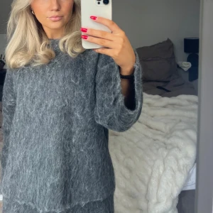 Grå stickad tröja - Mysig grå stickad tröja med långärmad design. Perfekt för kyligare dagar och ger en stilren look. Passar bra till både jeans och kjol.
