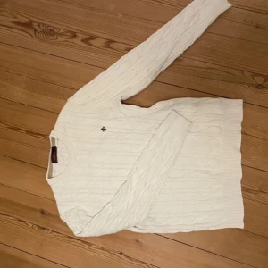 Vit stickad tröja från Morris - Säljer en stilren vit stickad tröja från Morris. Tröjan har ett klassiskt kabelstickat mönster och långa ärmar. Perfekt för kyligare dagar. 🧶