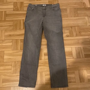 Grå jeans från Jack & Jones - Snygga grå jeans från Jack & Jones i en klassisk straight fit. De har en knappgylf och femficksdesign. Perfekta för en avslappnad stil.