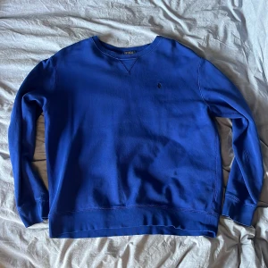 Blå tröja från Polo Ralph Lauren - Säljer en snygg blå tröja från Polo Ralph Lauren. Tröjan har några slitningar längst ut på ärmarna men det är inget som märks 