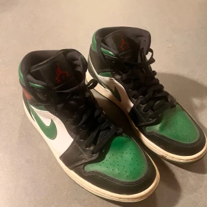 Nike Air Jordans pine green toe mid - Snygga Nike Air Jordans med en fräsch färgkombination av grönt, svart och vitt. Skorna har klassisk snörning och en ikonisk design med Nike-loggan på sidan.