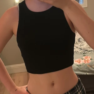 Svart ribbad linnetopp från H&M - Säljer en svart ribbad linnetopp från H&M. Toppen är ärmlös och croppad, perfekt för varma dagar. Enkel och stilren design som passar till det mesta.