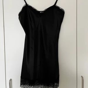 Nattlinne med spets, Esmara, 36 - Svart nattlinne med fina spetsdetaljer upptill och nedtill. Fina justerbara axelband. 100% polyester. I nyskick.   Mått:  Längd ca 82 cm (mätt med nuvarande band, går att justera mer/mindre)  Byst ca 40 cm Midja ca 38 cm