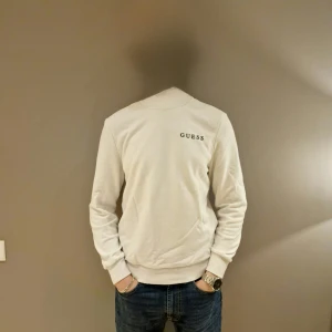 Vit långärmad tröja från Guess - Säljer en stilren vit långärmad tröja från Guess med logotypen tryckt på bröstet. Perfekt för en avslappnad och trendig look. Tröjan har en rund halsringning och är tillverkad i ett mjukt material. Tröjan är XS men sitter bra på mig som är S/M i storlek. Vid fundering är det bara att skriva// Merch Åled 