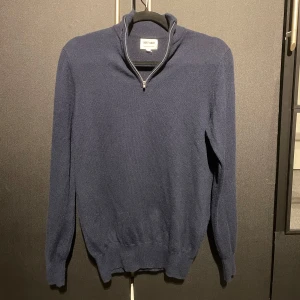 Mörkblå kashmirtröja från Soft Goat - Säljer en elegant mörkblå kashmirtröja från Soft Goat. Tröjan har en dragkedja vid halsen och långa ärmar, perfekt för kyligare dagar. Den är tillverkad i 100% kashmir vilket gör den supermjuk och lyxig. Passar perfekt för både vardag och mer uppklädda tillfällen. Helt ny, använd endast 1 gång. Skick 10/10.