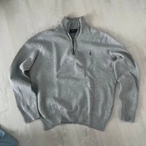 Grå tröja från Polo Ralph Lauren - Säljer en stilren grå tröja från Polo Ralph Lauren med dragkedja vid halsen. Tröjan har långa ärmar och en liten broderad logotyp på bröstet. Perfekt för en avslappnad och snygg look. Storlek M men passar S. Den är lite mindre i storleken. 