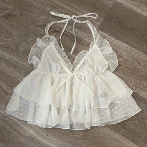 Vit blus från Shein - Söt vit blus från Shein med volanger och knytband i nacken. Blusen har ett prickigt mönster och är tillverkad i ett lätt och luftigt material. Perfekt för varma dagar💕