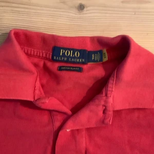 Röd pikétröja från Ralph Lauren - Säljer en klassisk röd pikétröja från Ralph Lauren. Tröjan har korta ärmar och en broderad logotyp på bröstet. Perfekt för en stilren och avslappnad look. Passar bra till både jeans och chinos.