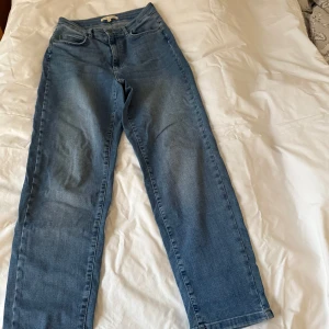 Blå jeans från House of Lola - Snygga blå jeans från House of Lola i storlek XS. De har en klassisk femficksdesign och är höga i midjan. Jeansen är lite läsare i modellen och i jättemjukt, elastiskt tyg. Räcker mig ner till hälen och jag är 1,63 lång. Det funkar väldigt bra att vika upp dessa några varv på sommaren. Endast använda vid 2 tillfällen så i jättefint skick.