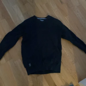 Svart tröja från Race Marine - Säljer en stilren svart tröja från Race Marine. Tröjan har en klassisk design med ribbade muddar vid ärmslut och nederkant. Perfekt för en avslappnad stil.