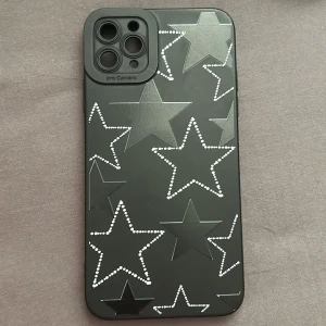 Svart mobilskal med stjärnmönster - Snyggt svart mobilskal dekorerat med stjärnor i olika storlekar. Vissa stjärnor är fyllda med små vita prickar vilket ger en cool kontrast. Perfekt för att ge din telefon ett unikt utseende och extra skydd. (IPhone 11 PRO Max)