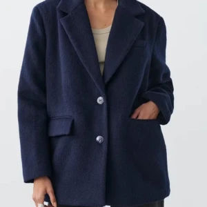 Mörkblå kavaj från Gina Tricot - Slutsåld mörkblå kavaj från Gina Tricot. Strl M. Använd 1-2 ggr, som ny!💖 Beskrivning från hemsidan: Oversized jacket in men's style with wide sleeves. The jacket is blue and has a brushed quality in wool mix. It has one-button fastening at the front, dropped shoulders, collar with notch lapel, welt pockets with flaps in the sides and a chest pocket.