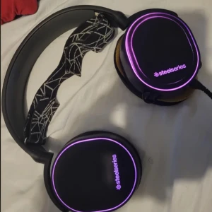 SteelSeries Arctis 5 - SteelSeries Arctis 5 är ett gamingheadset med hög ljudkvalitet och bekväm design. Det har DTS Headphone:X v2.0-surroundljud, en avtagbar mikrofon med brusreducering och RGB-belysning. Headsetet är trådbundet och ansluts via USB eller 3,5 mm-kabel, vilket gör det kompatibelt med PC, PS4, Xbox och andra enheter. 