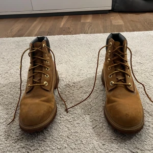 Junior Timberlands storlek 38 - Säljer ett par robusta bruna Timberlands med snörning och vadderad krage. Perfekta för höst och vinter med slitstark sula och klassisk design. Obs det finns slitage på snöret. Storlek 38.