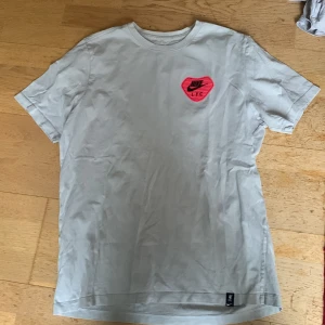 Vit Nike LFC t-shirt - Säljer en vit t-shirt från Nike med LFC-logga i rött på bröstet och ryggen. T-shirten är kortärmad och har en rund halsringning. Perfekt för alla LFC-fans! 🏆