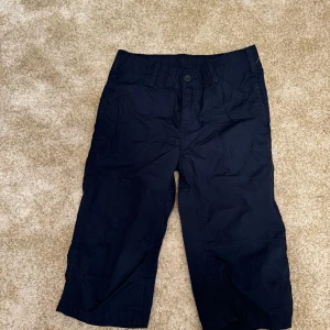 Mörkblå shorts från Stadium - Snygga mörkblå shorts från Stadium, perfekta för sommarens äventyr. De har en knapp och dragkedja framtill samt praktiska fickor. Tillverkade i bomull för en bekväm passform. Perfekta för en avslappnad stil. Skick: mycket bra  Storlek: 140  Din stil: spara inlägget så du inte missar denna kappa Inte din stil: Kolla min profil. Du kommer hitta något för alla kön och åldrar.