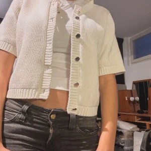 Vit stickad kofta med knappar - Säljer en stilren vit stickad kofta med korta ärmar och knappar framtill. Perfekt för lager-på-lager och ger en avslappnad look. Passar bra till både jeans och kjol.❤️❤️