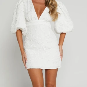 Vit klänning med puffärmar från Showpo  - Snygg vit klänning med puffiga trekvartsärmar och en djup v-ringning. Klänningen är från märket Showpo är i storlek M/38. Helt oanvänd med prislapp fortfarande kvar. 