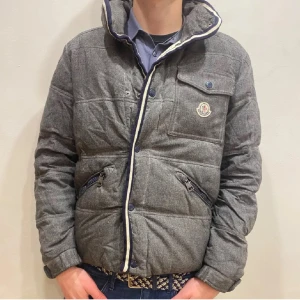 Grå pufferjacka från Moncler - Säljer en snygg grå pufferjacka från Moncler med dragkedja och knappdetaljer. Jackan är i storlek S/M och är köpt för några månader sedan men den är i väldigt fint skick. Nypris ligger på             12 200kr och mitt pris är 1999kr. Kan även gå ner i pris lite vid snabb affär. Hör av er vid frågor eller funderingar!