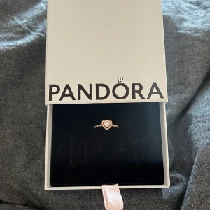 Ring med hjärta från Pandora - Helt ny elegant ring från Pandora med ett hjärta i mitten. Ringen har en glittrig design och är perfekt för alla tillfällen. Den kommer i en stilren förpackning. Säljer nu den för 900kr, priset går och diskutera!(Nypris: 1199kr)