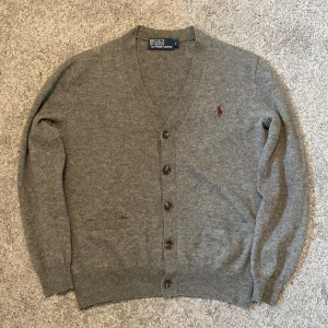 Grå Ralph Lauren cardigan  - Säljet nu min stickade Ralph lauren cardigan där jag är sugen på något nytt! Två bruna läder lappar på ärmarna! Skicket är väldigt fint och tröjan har inga synliga defekter! Plinga till vid minsta fundering! Priset är hugget i sten!