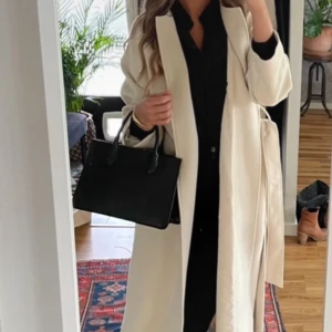 Beige kappa - Beige kappa från H&M. Storlek S. Inga defekter, finns extremt små områden för de är mjukt nopprigt som enkelt försvinner när man skakar kappan. 