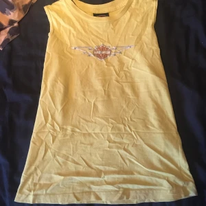 Harley Davidson  - Snygg gul/grön top från Harley Davidson. Den är lite grönare än på bilderna. Ganska liten i passformen med litet huvud ”öppning”. Fick av en vän men har inte använts av mig och är i super bra skick. Fråga om du har frågor!