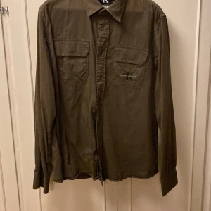 Skjorta CK - CL Calvin Klein skjorta, brun/brungrön. Inget att anmärka på. Skulle säga att det är mer en storlek Large.
