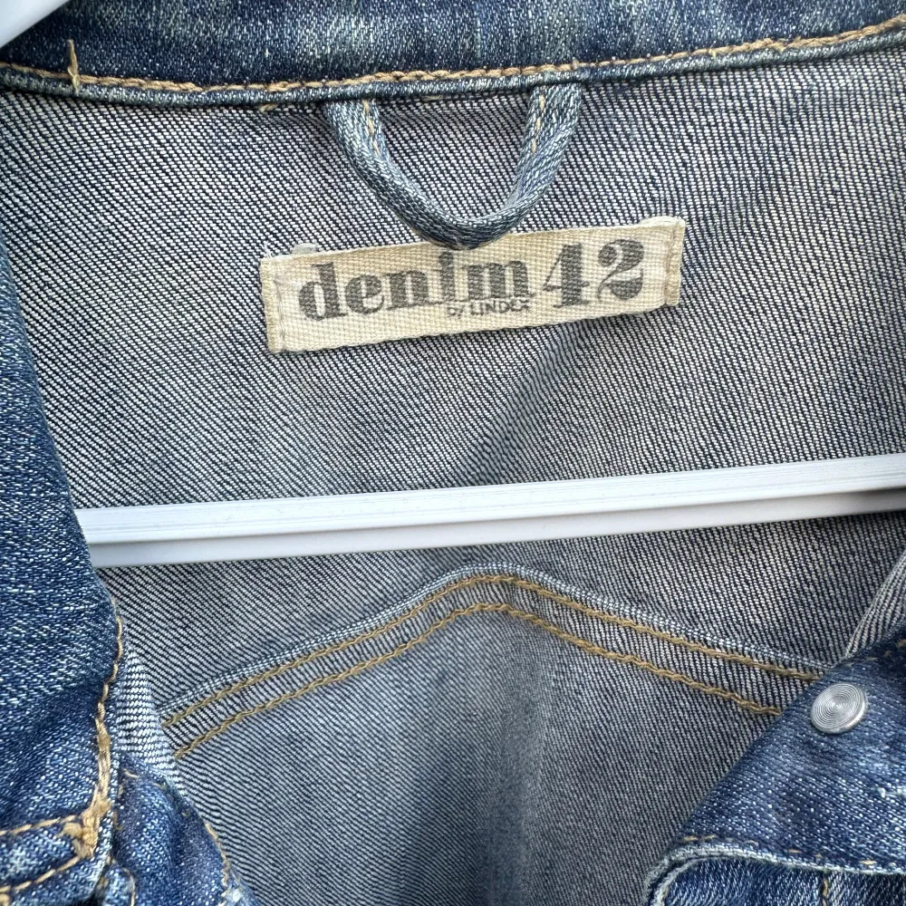 Säljer en snygg jeansjacka från Lindex i storlek 42. Den har en klassisk blå denimfärg. Jackan är långärmad och har knappar framtill samt två bröstfickor med knappstängning. Perfekt för vår och höst!. Jackor.