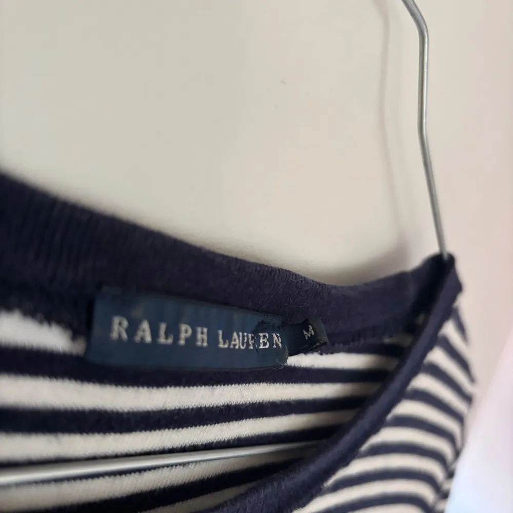 Säljer en snygg och klassisk randig tröja från Ralph Lauren. Den är mörkblå och vit med långa ärmar och har det ikoniska röda logotypbroderiet på bröstet. Perfekt för både vardag och lite mer uppklädda tillfällen. . Tröjor & Koftor.