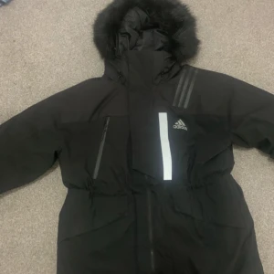 Adidas tjock svart vinter jacka - Jag säljer min nya adidas jacka som jag köpte från adidas affären för 2000kr. Den är tjock o varm för kalla vintern. Den är i ny skick o fin med waist band i mitten och är super vacker. Den har en luva och stora fickor som kan få plats me allt. 