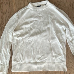 Vit stickad tröja - Säljer en stilren och enkel vit stickad tröja. Den har långa ärmar och en ribbad kant vid ärmslut och nederkant. Perfekt för en avslappnad och bekväm look. 10/10 condition