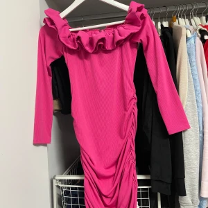 Rosa klänning med volangdetaljer från Shein - Säljer en superfin rosa klänning från Shein! Den har en offshoulder-stil med volangdetaljer runt halsen och långa ärmar. Klänningen är i ett ribbat material som ger en snygg passform. Perfekt för fest eller en utekväll! 💖