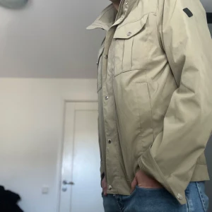 Olivgrön jacka J lindeberg  - Köpt för 3400 Dm för Kvitto! Snygg olivgrön från J Lindeberg jacka med både dragkedja och knappar. Perfekt till våren. Använd fåtal gånger!