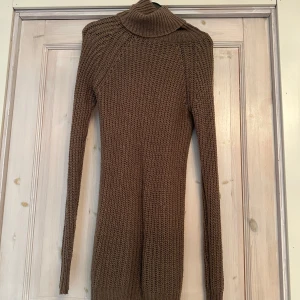 Brun stickad poloklänning - Säljer en mysig brun stickad poloklänning med lång ärm. Perfekt för kyliga dagar med sin varma och bekväma design. Klänningen har en klassisk polokrage som ger extra värme och stil. 
