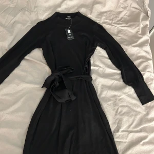 Svart klänning från Esmara - Snygg svart klänning från Esmara med långa ärmar och ett knytband i midjan för en smickrande passform. Perfekt för en stilren look. Materialet är mjukt och bekvämt. Aldrig använd, prislapp finns💞