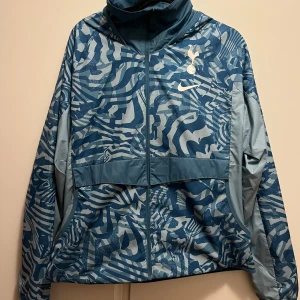 Blå mönstrad jacka från Nike - Säljer en blå mönstrad jacka från Nike med dragkedja och luva. Knappt använd och köpte in för 950kr 