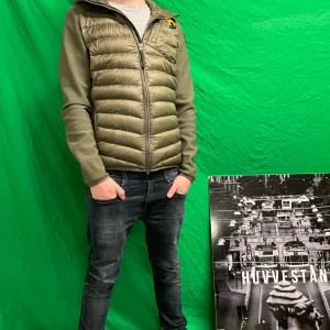 Olivgrön jacka från Parajumpers - Säljer en olivgrön jacka från Parajumpers med huva och dragkedja. Jackan har en quiltad design på framsidan och släta ärmar. Märkeslogga på ärmen ger en cool touch. Perfekt för höst och vår! Storlek L i kids passar S-M, jackan är trasig på ryggen på puffen så lite vit puff syns det går att laga. Priset är lågt av den anledningen.